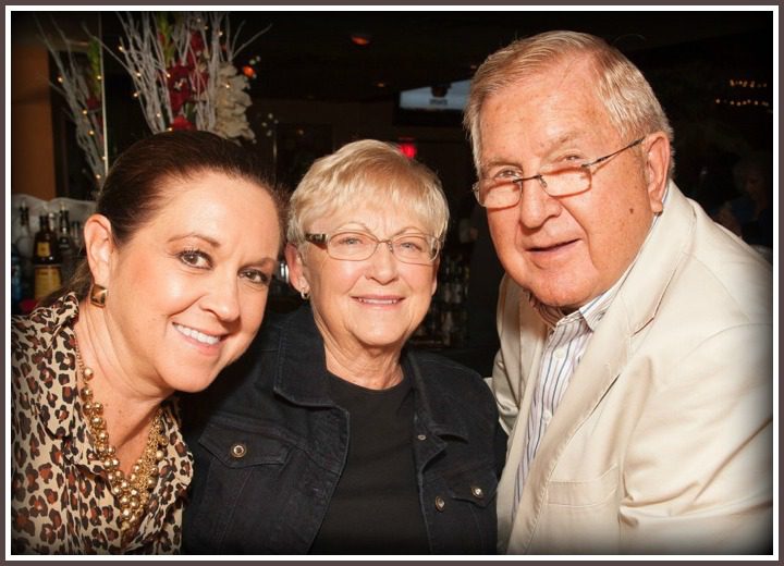 A Group of Individuals at a Social Gathering With a Dimly Lit Background Resembling a Bar or Restaurant Setting.